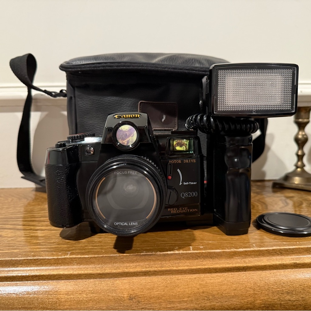 Vintage Canon camera with a flash attachment and carrying case.